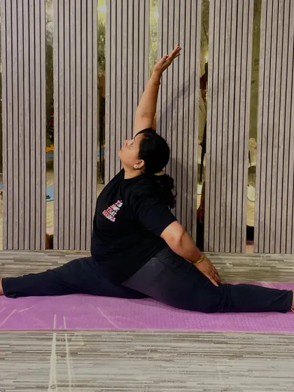This is a seated wide-legged forward bend with a twist (Parivrtta Upavistha Konasana), an amazing pose for stretching the hamstrings, spine, and shoulders. It shows the kind of deep flexibility we work towards.