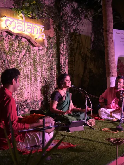 A different perspective of the Namma Ashram concert, showing the artists seated on the grass stage. This informal setup creates a very relaxed and engaging atmosphere.