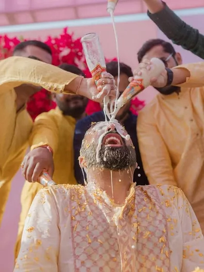 The groom's friends shower him with beer during a wild Haldi celebration, a moment of pure, unscripted fun.