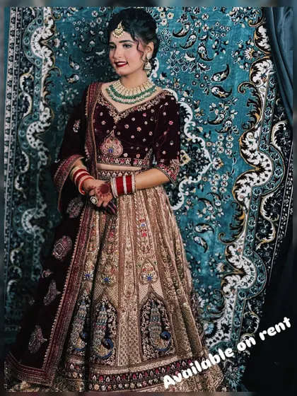 A beautiful dual-tone bridal lehenga with a maroon velvet blouse and a beige skirt featuring peacock motifs. This outfit is available for rent to make your wedding day perfect.