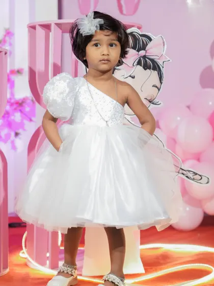 This full-length shot shows the beautiful silhouette of the custom one-shoulder dress. The voluminous skirt is light and airy, perfect for a little one who loves to dance and play at her party.