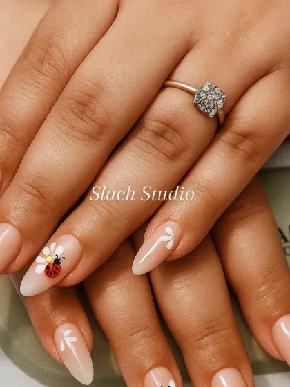A touch of whimsy on these nude almond extensions. I hand-painted delicate white flowers and added a cute ladybug design on the ring finger for a unique and charming look.