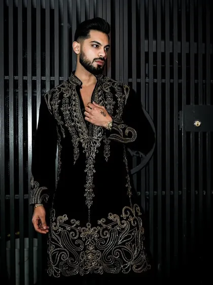The deep black velvet of this kurta set provides the perfect canvas for the shimmering gold embroidery. The design is opulent and sophisticated, ideal for a grand Diwali party or a wedding sangeet.