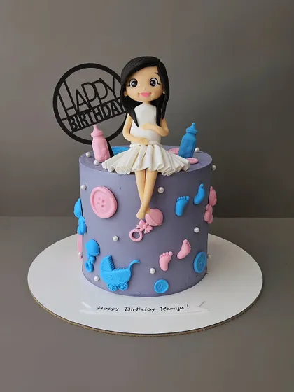 A special birthday cake for a mom-to-be. This chocolate truffle cake is decorated with baby items and a figurine of the expecting mother, celebrating her and the baby on the way.