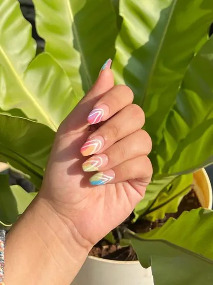 Another shot of the client enjoying her custom rainbow press-on nails. The vibrant colors and crisp white lines make this a perfect set for a sunny day.