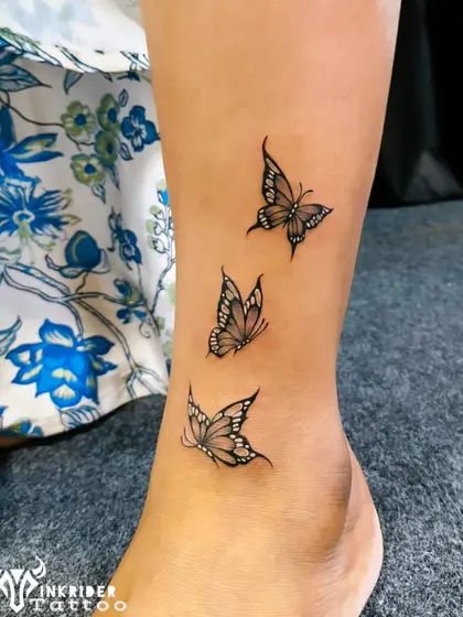 A trio of delicate butterflies fluttering up the ankle. This fine-line tattoo is a graceful symbol of change and beauty.