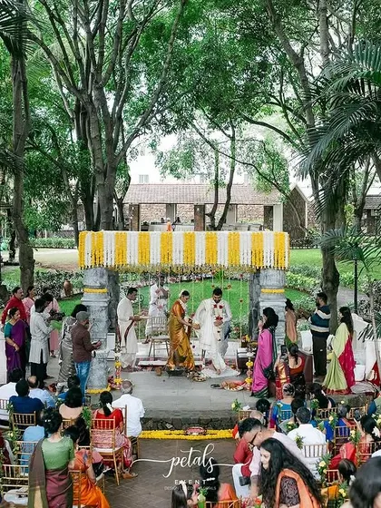 A beautiful moment during the saptapadi ceremony at Angana the Courtyard. The temple-themed decor, with its fragrant blooms and traditional elements, provides a sacred backdrop for the couple's vows.