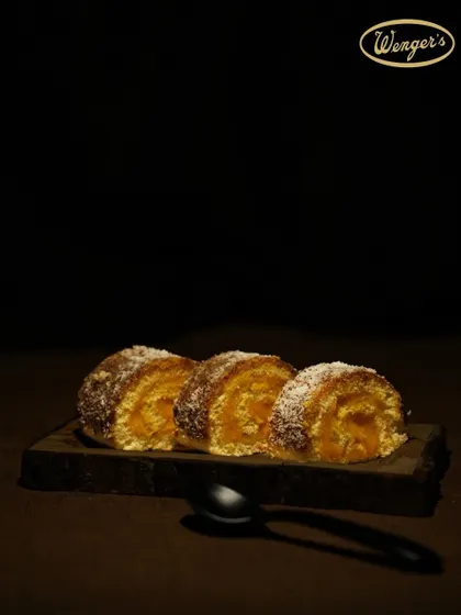 A Lemon Swiss Roll, offering a lighter, tangier alternative. The zesty lemon cream is rolled into a soft sponge and dusted with coconut.