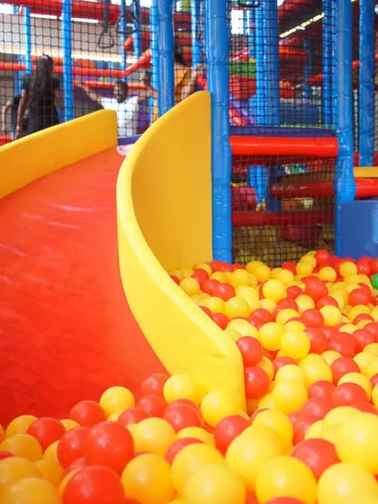 A bright red slide ready for action, ending in a sea of colorful balls. Our slides are a highlight for many kids, offering a thrilling ride every time.