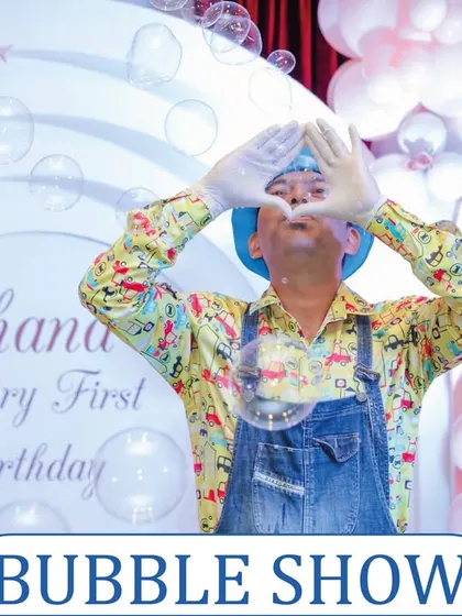 A bubble show entertainer making a heart shape with his hands, surrounded by floating bubbles. It's a performance filled with charm and wonder.