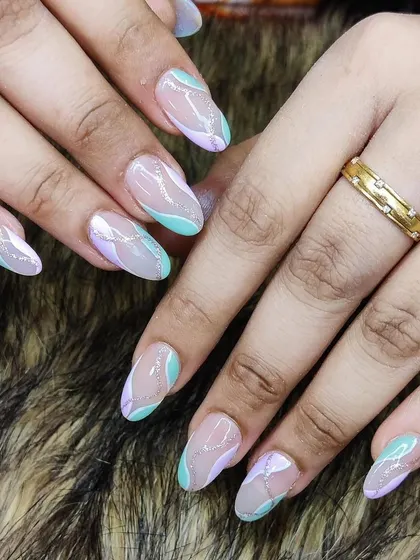 A soft and dreamy abstract design, featuring pastel green and lilac swirls with a touch of silver glitter on almond-shaped nails.