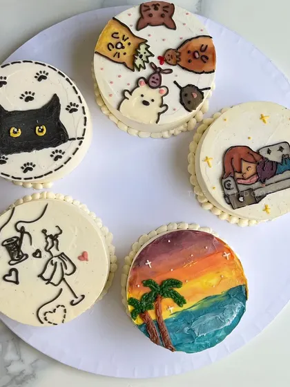 A collection of some of my favorite custom-doodled mini cakes. From cats and sleepy characters to fashion designs and sunset paintings, I can pipe almost anything onto a cake to match your personality.