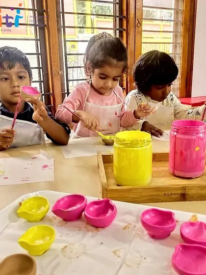 Children wearing aprons paint clay diyas for Diwali. This cherished tradition allows them to engage in a multi-step creative process, from pottery to painting.