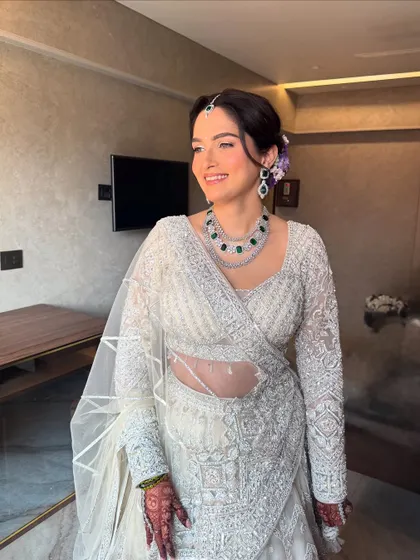 A full-length view of this elegant ivory reception look. The makeup is timeless, ensuring she looks graceful and beautiful throughout her celebration.