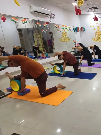 A class working on a revolved side angle stretch, using yoga wheels and blocks for support. Props help everyone find the right variation for their body, ensuring a beneficial and safe practice.