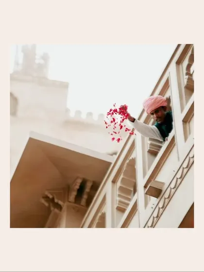 A symbolic shot of rose petals being showered from a palace window in Jaipur, setting a romantic and regal tone for the wedding festivities to come.