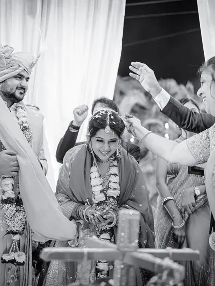 A happy moment during a wedding ritual, with family members blessing the couple. Captured in classic black and white.