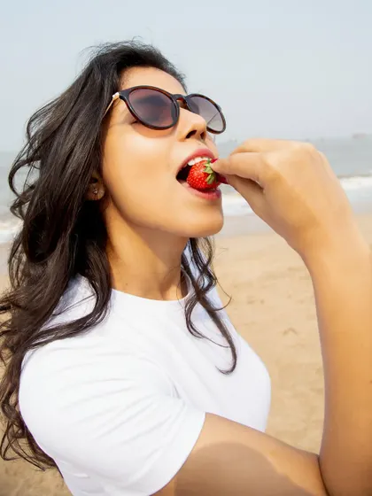 A close-up, sensory shot of eating a strawberry, perfect for food, beauty, or lifestyle brands wanting to evoke a feeling of summer.