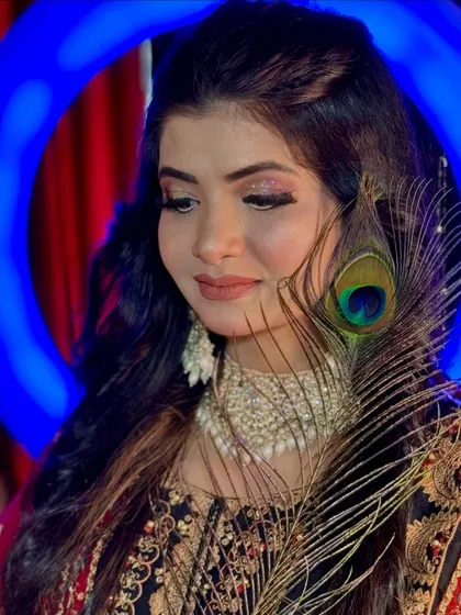 A soft and dreamy portrait. The pink-toned eyeshadow and nude lip create a romantic feel, enhanced by the artistic use of the peacock feather.