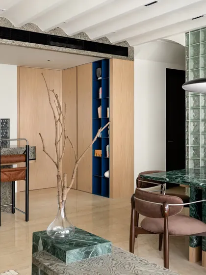 A view from the dining area, showing the connection to the living room and the custom shelving unit. The space is designed to be inclusive and engaging.