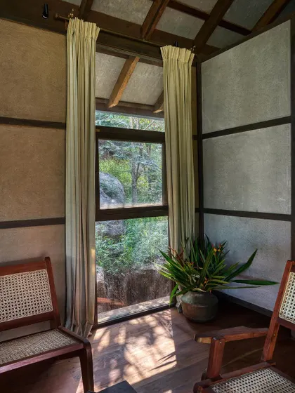 A quiet corner with cane chairs looking out through a large window. Every opening in the home is designed to frame a view, making the landscape an integral part of the interior design.