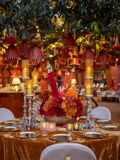 A vibrant centerpiece from a traditional Indian event, featuring silver candelabras, textured floral spheres, and intricate jasmine beadwork. The design is a rich tapestry of color and craftsmanship.