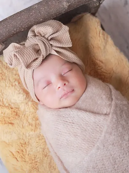 An overhead close-up of the baby in a large bow headband, part of our 'Wooden Era' collection. We have a wide variety of accessories to style your session.