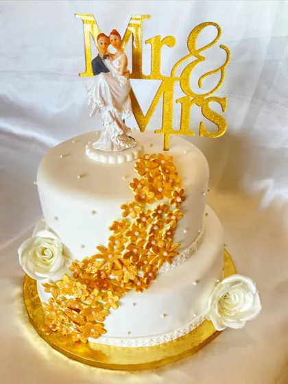 This two-tier wedding cake was based on an inspiration picture from the client. I added my own touch with cascading golden flowers and a classic couple topper to make it truly special for their big day.
