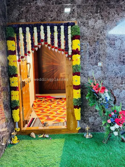 A colorful door frame decoration using yellow and purple flower garlands, creating a vibrant welcome for guests.