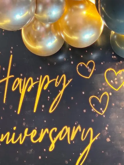 A close-up of the 'Happy Anniversary' neon sign against a sparkling black backdrop, adding a personalized and warm glow to the celebration.