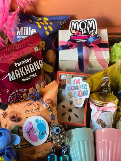 A detailed look inside the mom-to-be trunk. You can see the variety of snacks, a scented candle, and cute stickers like "I'm Coming Soon" and "Mom to be".
