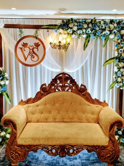 A closer look at this personalized engagement stage, highlighting the custom 'V&S' monogram. The combination of a traditional carved sofa with modern floral stands creates a balanced and stylish look.