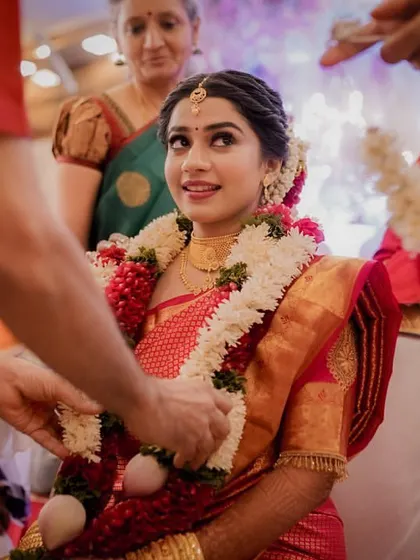 A beautiful moment as the bride is adorned with a garland during the ceremony, her upward glance filled with emotion.