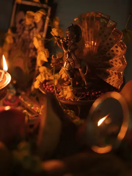 A detailed shot of the Krishna idol within the Vishu kani arrangement. The selective focus and moody lighting create a sense of reverence and devotion.