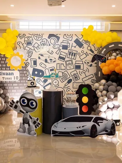 A modern and cool tech-themed party for a 10th and 8th birthday. The decor features elements like robots, gaming controllers, and car cutouts.