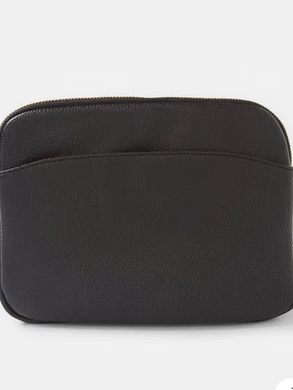 A front view of the Australia Crossbody bag in black. It features a simple, clean design with a front slip pocket and a secure zip top.