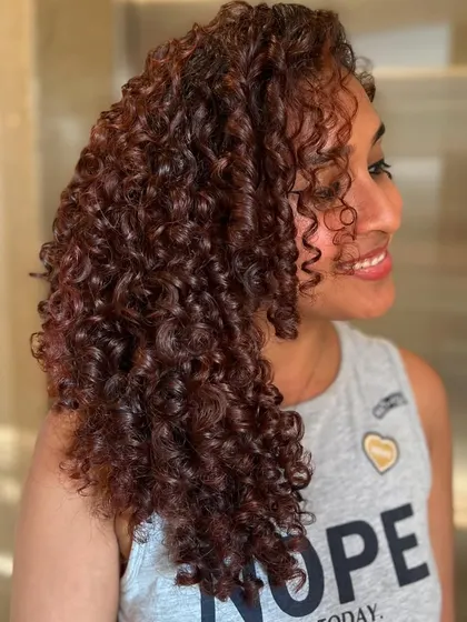 A side view of the Pumpkin Spice curly transformation. The color is vibrant, and the client's smile says it all.