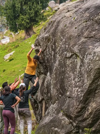 A climber in our Sethan valley workshop focuses on her footwork and handholds, with spotters ready below. We teach the fundamentals of outdoor bouldering in a safe and encouraging environment.