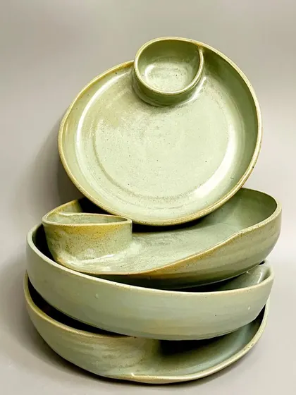 A stack of my green glazed chip-and-dip platters. The way they stack shows their consistent form, while the unique glaze on each piece highlights their handmade quality.