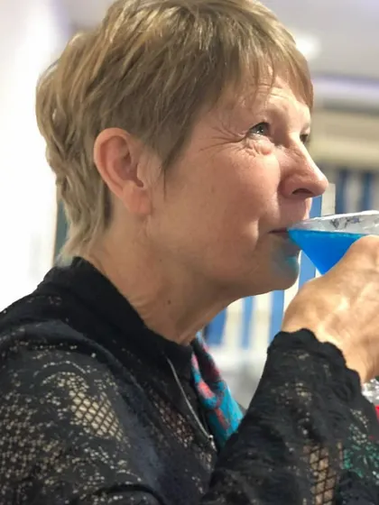 A guest savoring a vibrant blue cocktail during a party. My aim is to create drinks that are not only delicious but also a conversation starter.