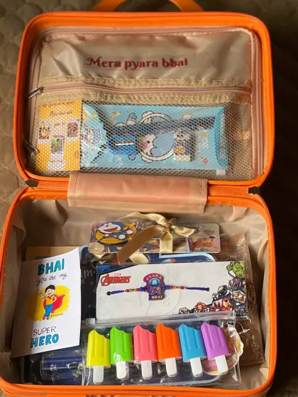 This Rakhi suitcase hamper is themed for a younger child, with a "Bhai you are my Super Hero" card, an Avengers Rakhi, and cute popsicle-shaped highlighters.