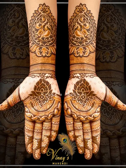 A different style of peacock mehndi, with the birds framed in a heart-like shape on the back of the hands. The design is simple, elegant, and modern.