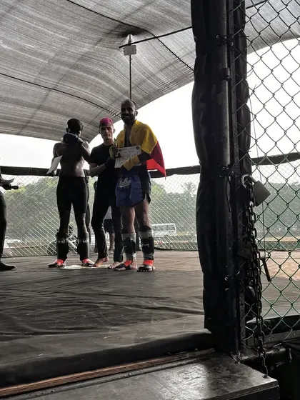 A fighter receiving his certificate after a comeback win, surrounded by his teammates. This is the support system we build.