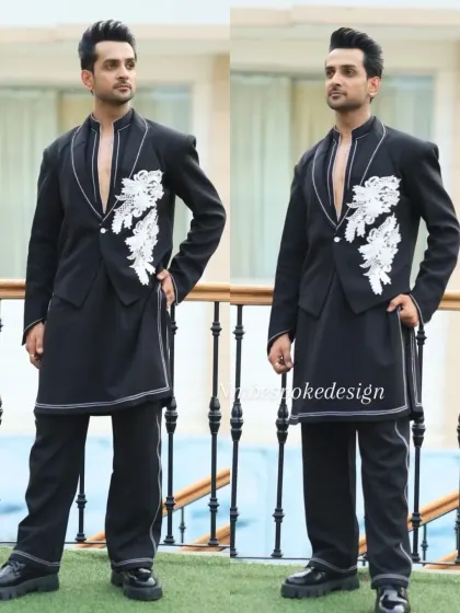 A modern, edgy take on the waistcoat. This black open-front piece is layered over a longline kurta and features white floral appliqué and contrast stitching.