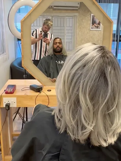 A look in the mirror at a client's silver hair transformation.