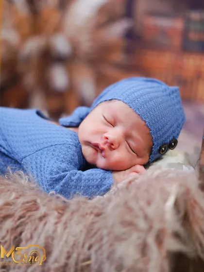 Another angle of the baby in the blue knit outfit, showing the cute button details on the hat.