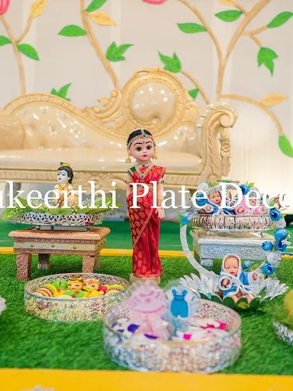 A wider view of the baby shower setup, showing the variety of platters and props used. From baby dolls in cradles to beautifully arranged sweets, every element is thoughtfully placed.