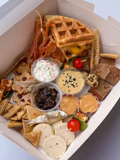 My dog-friendly grazing board is a feast for the senses. This one is packed with homemade chicken jerky, dehydrated anchovies, bread sticks, gourmet dips, carob peanut butter cups, and even a monster waffle burger.