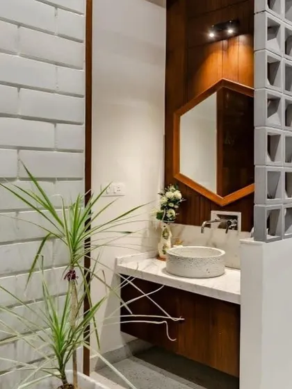 I used a combination of white brick tiles, a jali block partition, and a wooden vanity to create a unique, rustic-modern bathroom. The hexagonal mirror adds a contemporary geometric touch.