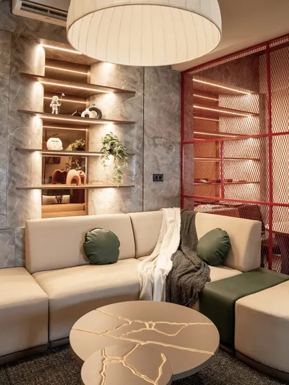 This cozy lounge area in our office is designed for informal meetings and relaxation, featuring a comfortable sectional, integrated shelving with warm backlighting, and a unique kintsugi-inspired coffee table.